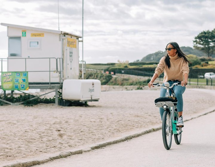 A young man and a woman riding bikes along the beach