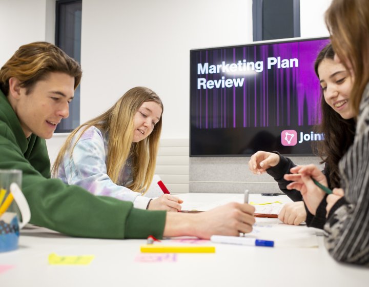 Group of students sat round a table mind mapping 