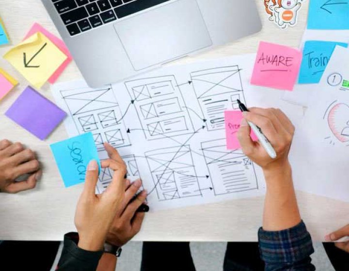 Students drawing UX Design diagrams on a piece of paper 