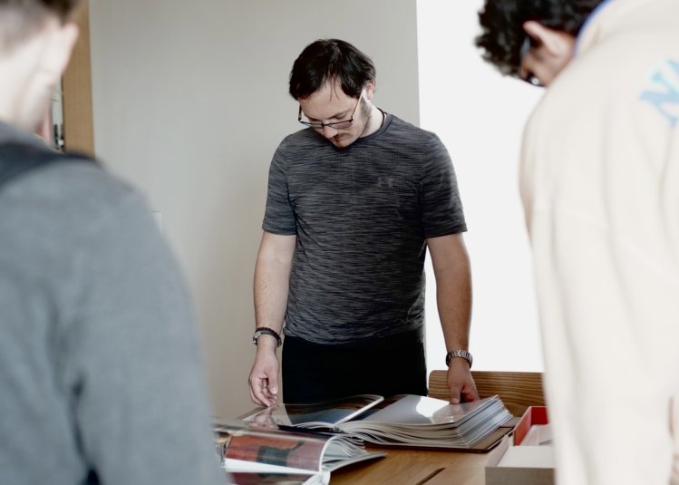 Three Falmouth University commercial photography students looking through portfolios