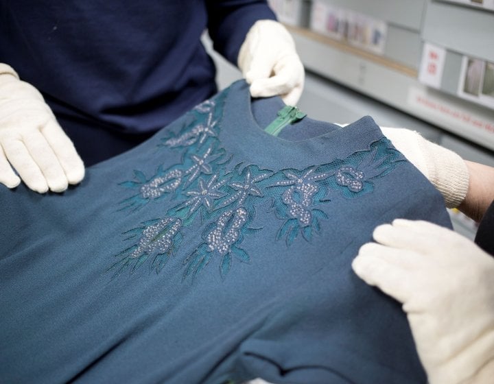 Close crop of two people wearing white gloves examining a garment in the Textiles & Dress Collection