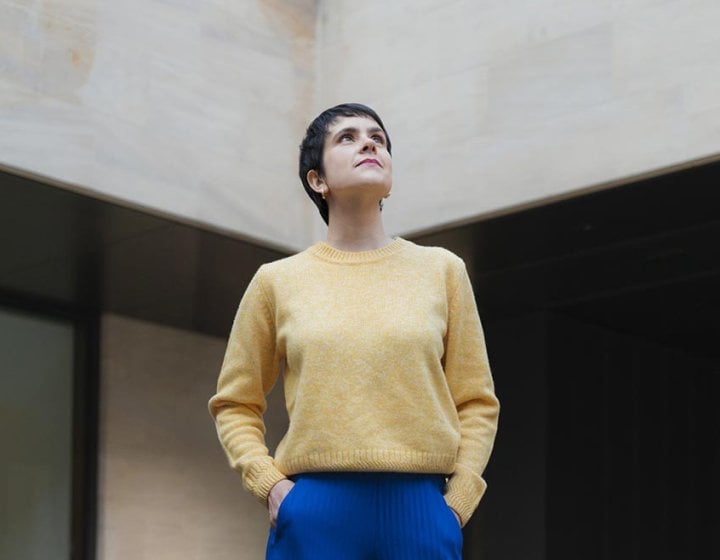 A woman wearing a yellow jumper and blue trousers