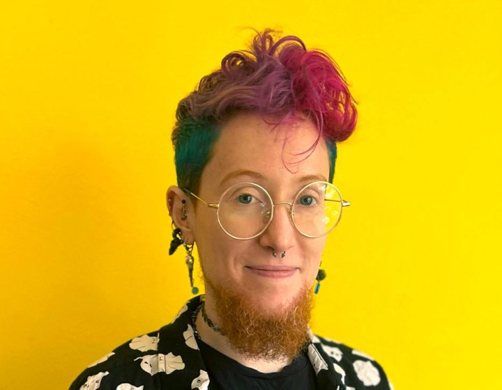 A person smiling into the camera against a yellow background