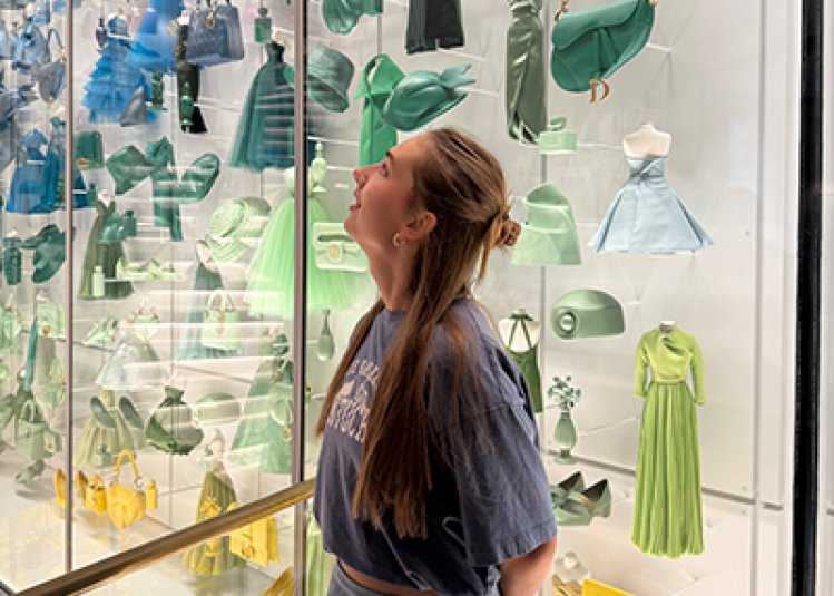 Student with blonde hair in front of colourful exhibition