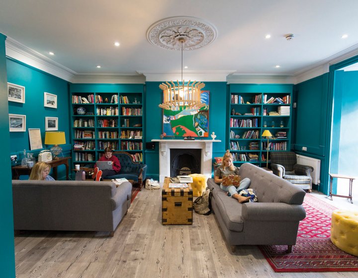 Students sat on sofa in a room full of books