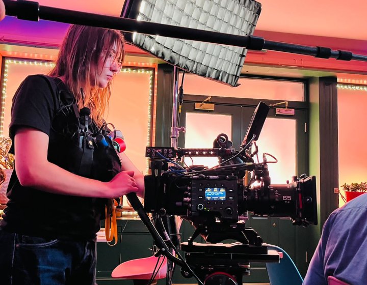 Film graduate Faith Glenister operating a camera on a film set