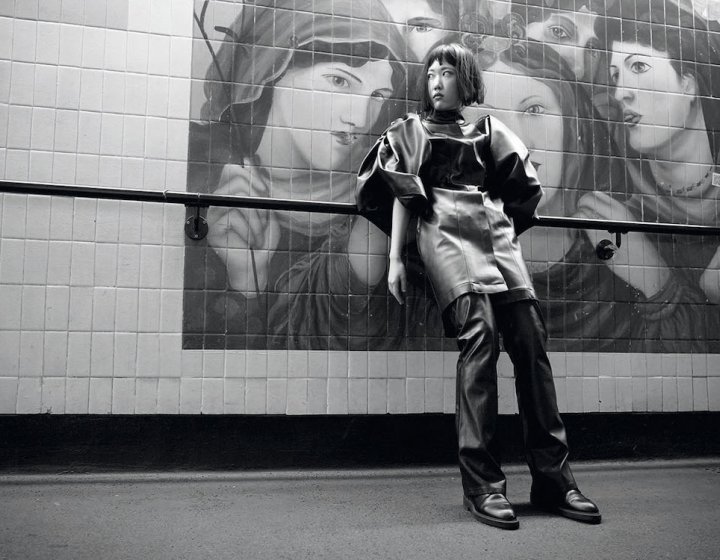 Fashion model posing in front of a mural of pre-raphelite women