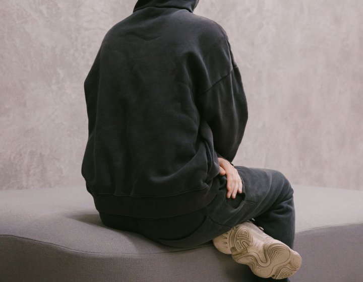 Photo of Fashion Design graduate Finlay Vincent facing away from the camera wearing black hoody with the hood up.