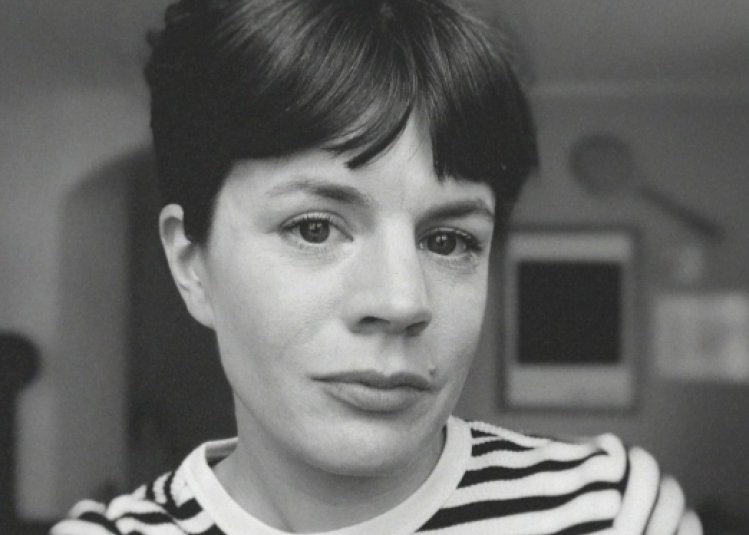 A woman with dark hair wearing a stripy top looking into the camera