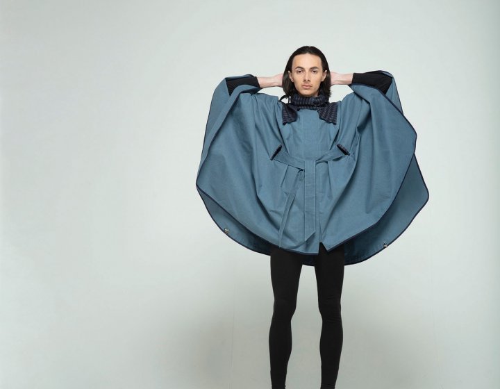 Model wearing cape design with hands behind head