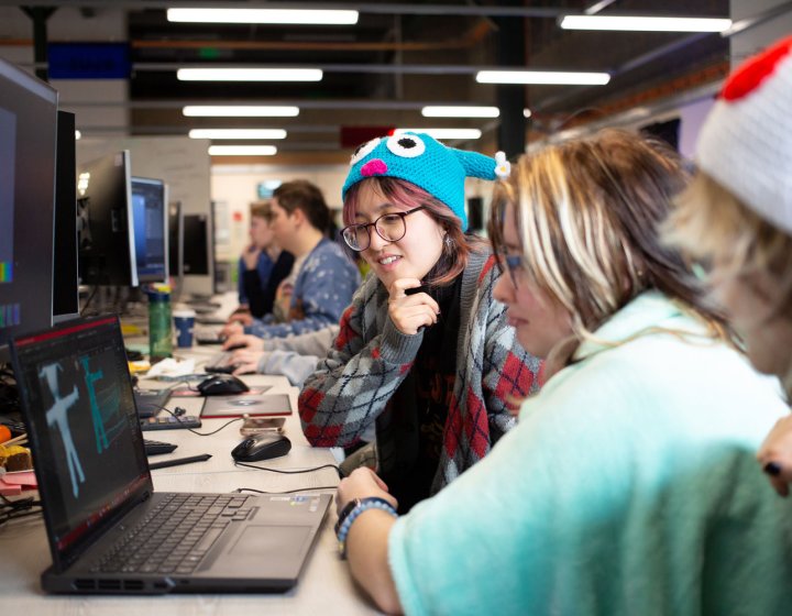 Three Falmouth University students around a computer at the 2025 Games Jam