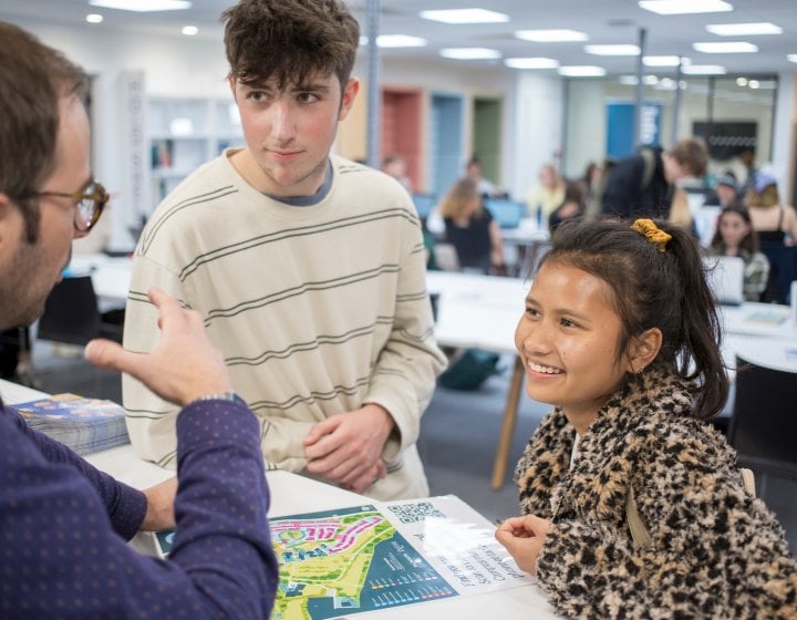 Two students speaking a staff member in The Compass