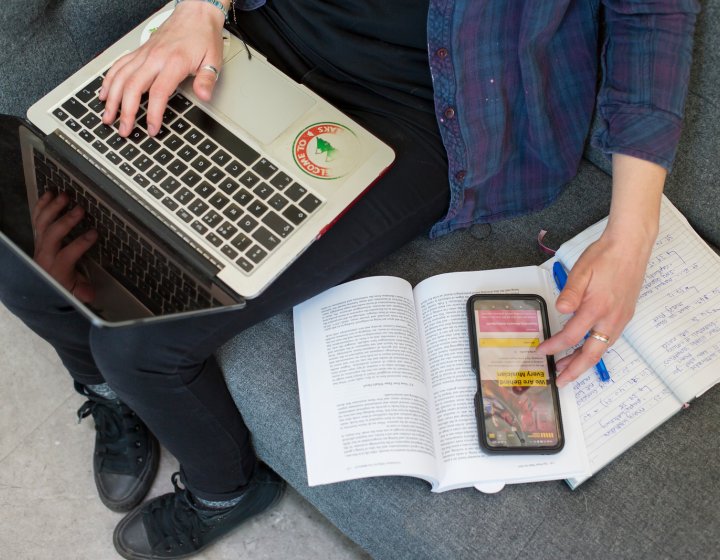 A student working on their laptop while looking at some textbooks