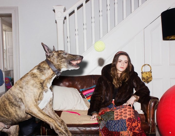 A young woman sitting on a sofa with a large dog jumping up