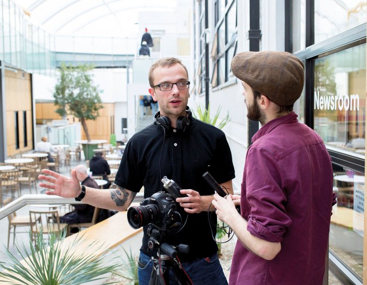 Students chatting and holding recording equipment