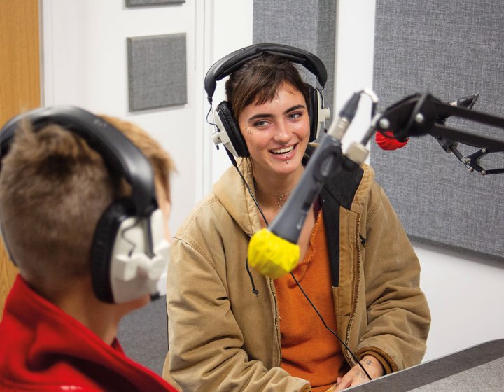 Students with headphones laughing and speaking into microphone