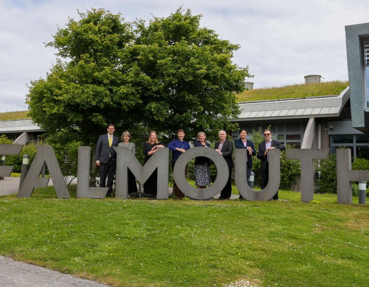 Delegates from LASALLE and Falmouth University standing behind large concrete letters reading 'FALMOUTH'