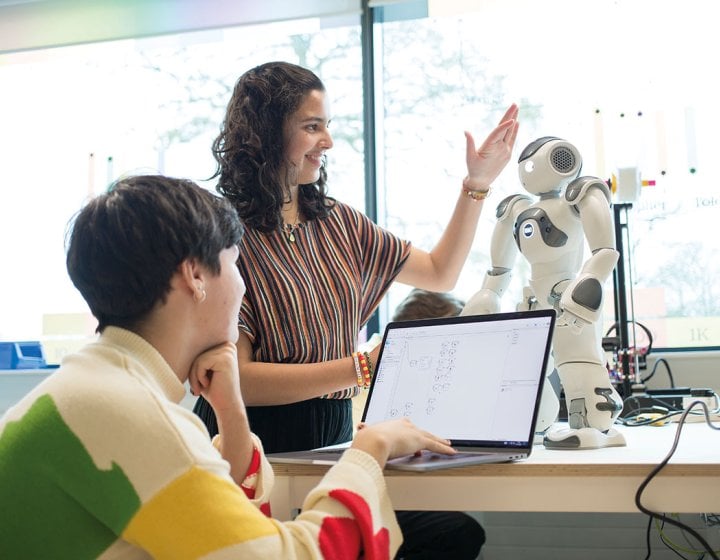 Robotics students discussing with robot on desk