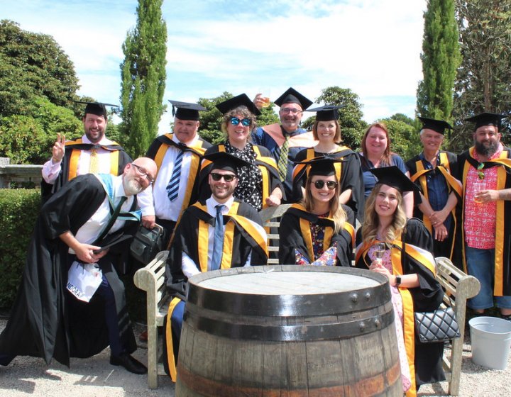 A group of graduating students wearing gowns gather together