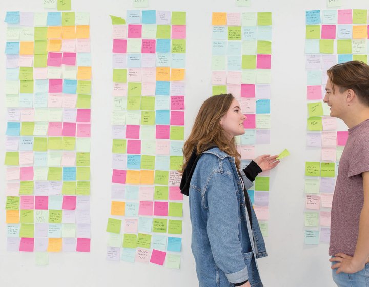 Students stood by a wall of post it notes
