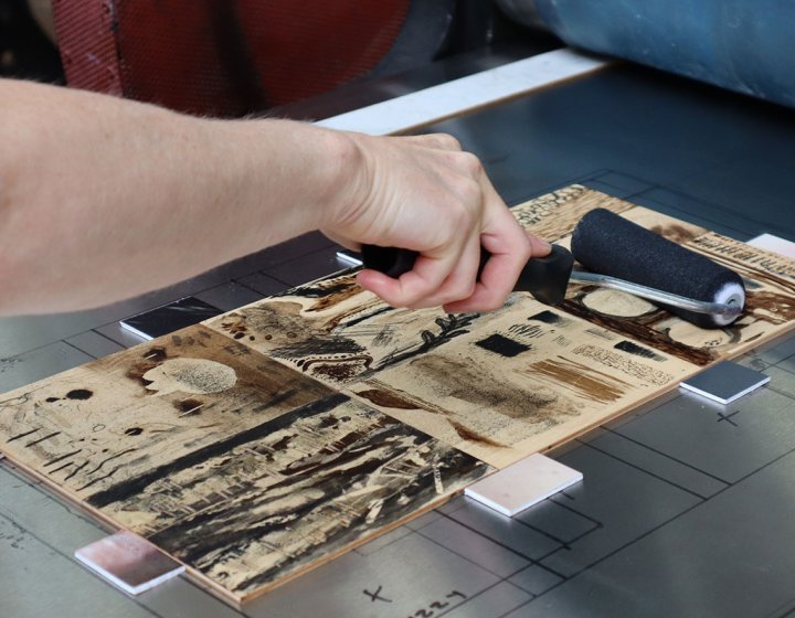 Someone inking a wood cut for mokulito