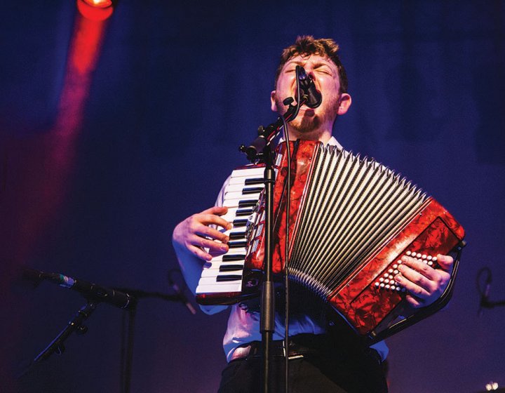 Student singing into microphone and playing accordion