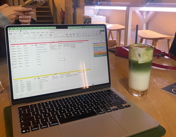 A laptop with excel open and a drink next to it