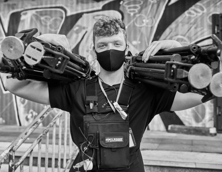 A student holds camera tripods on a tv set 