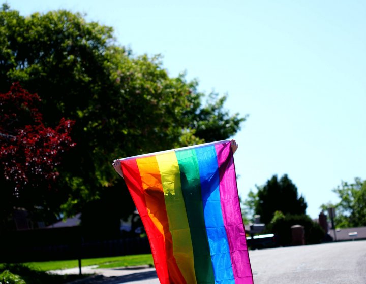 A pride flag is draped over shoulders