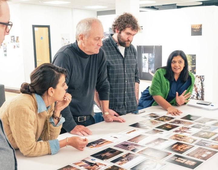 A group of people looking at photos on a table