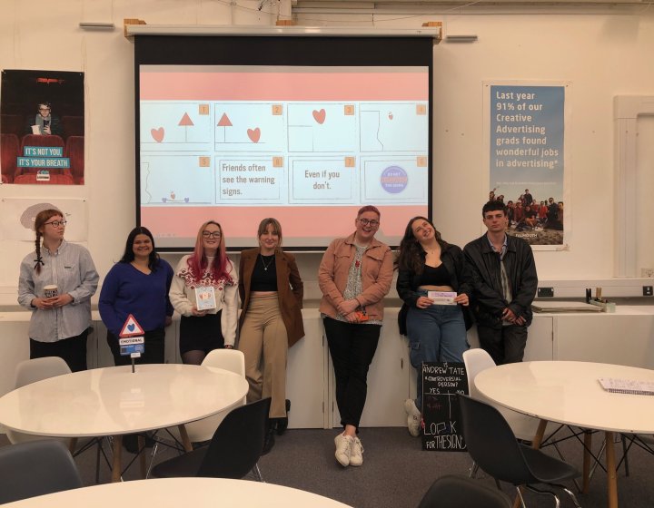 A group of Creative Advertising student standing in front of a screen in a seminar room