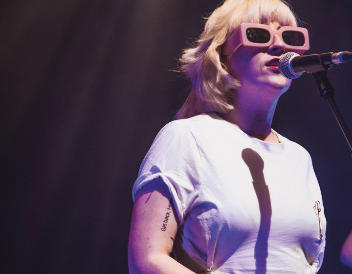 Blonde singer with sunglasses stood at microphone