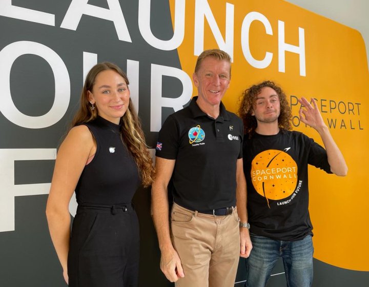 Graduate Rachel Harrison and student Ben Pisacane stand either side of Time Peake in front of backdrop that reads 'Launch our future'.