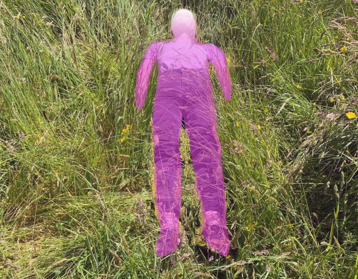 image: @josiecockram ‘after Ana Mendieta’. A field of grass with purple person lying in the grass