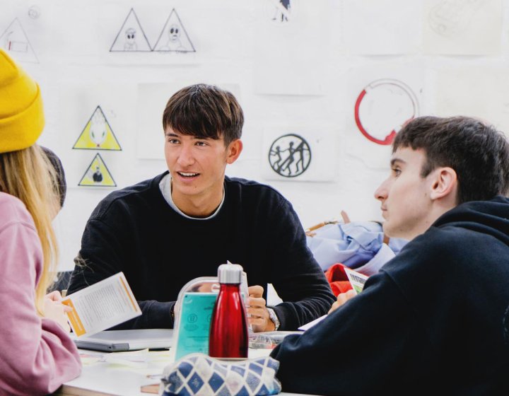 Three students gathered round a table at Falmouth University