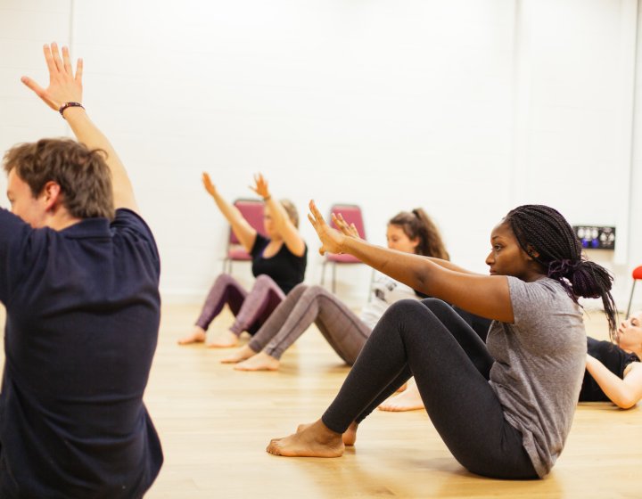 Group of people sitting in a studio doing a stretching exercise