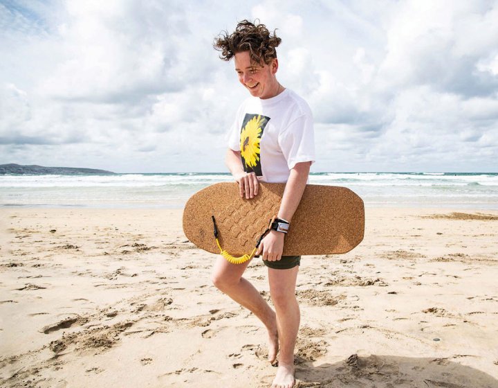 Model carrying cork bodyboard on beach