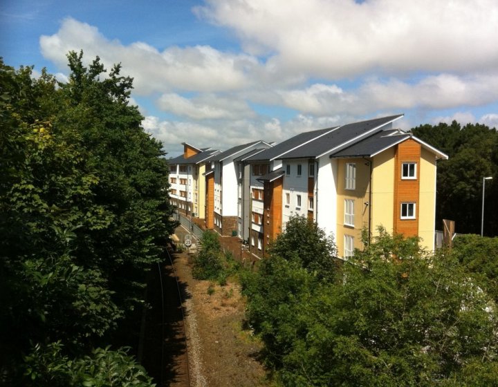 A building opposite train tracks and surrounded by trees