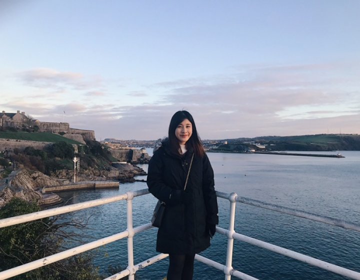 A woman poses in front of the ocean