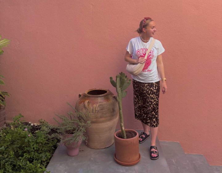 A woman stood outside a pink building 