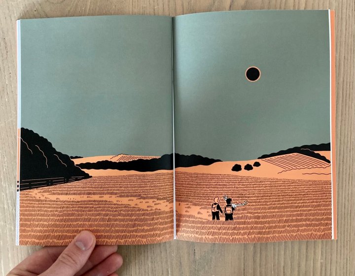 Open page of comic book showing double page spread illustration of a landscape with blue sky, orange land and black trees.