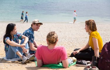 Falmouth University students relaxing on the beach