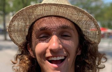 Falmouth University student smiling, wearing a straw hat