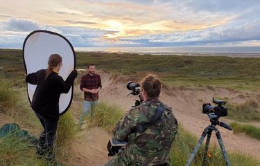 Students filming on beach