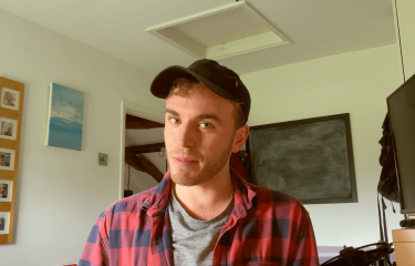 A Falmouth University student wearing a baseball cap and red checked shirt