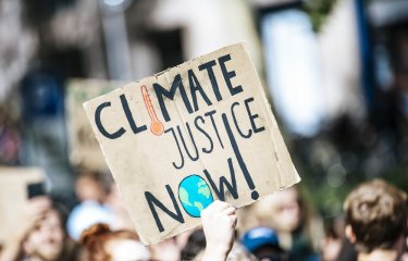 Image of protest placard reads 'Climate Justice Now'