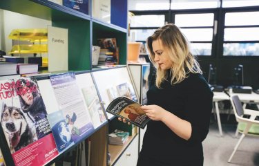 A Falmouth University student looking through a Postgraduate study guide