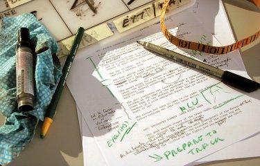 A printed piece of paper with green ink annotations and pens