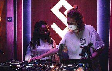 Graduate DJ Daisy Moon at the decks with another woman.