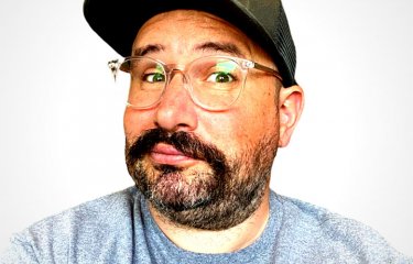 Headshot of Don't Cry Wolf founder John Brown. John wears a t-shirt and baseball cap
